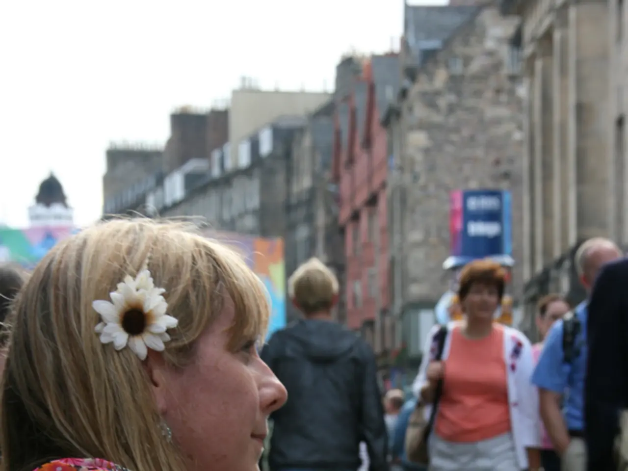 It is an open place where people are walking on the streets. One woman is sitting and playing a...