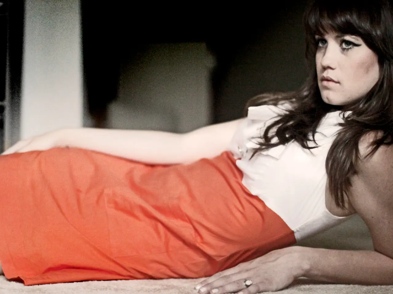 In this image I can see a woman. She is wearing a white shirt and an orange skirt.