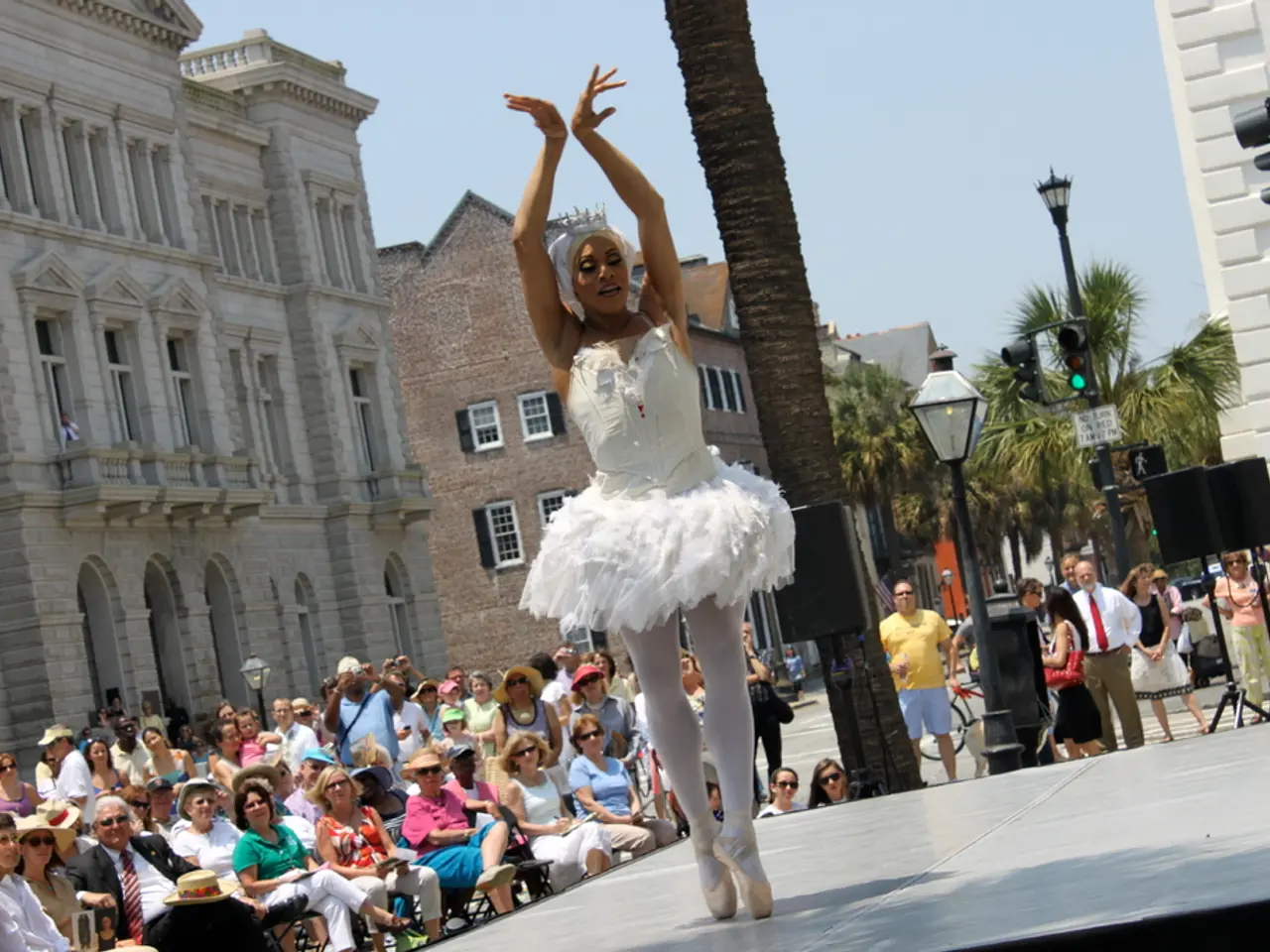 In this image we can see a lady person wearing white color dress dancing and there are some group...
