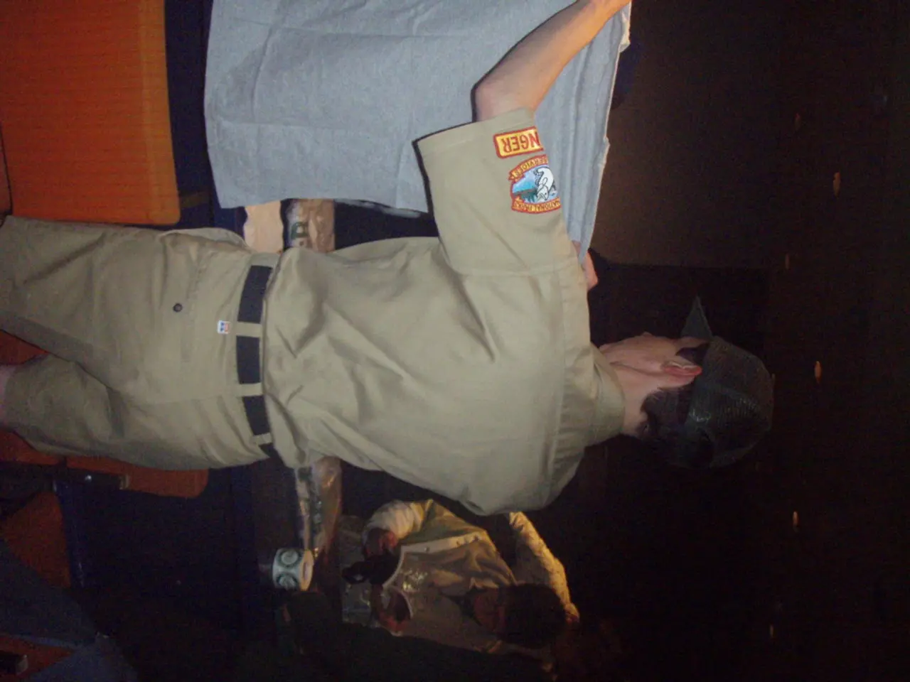 There is a cop holding a T- shirt in the foreground and a boy holding a book, a mug, it seems like...