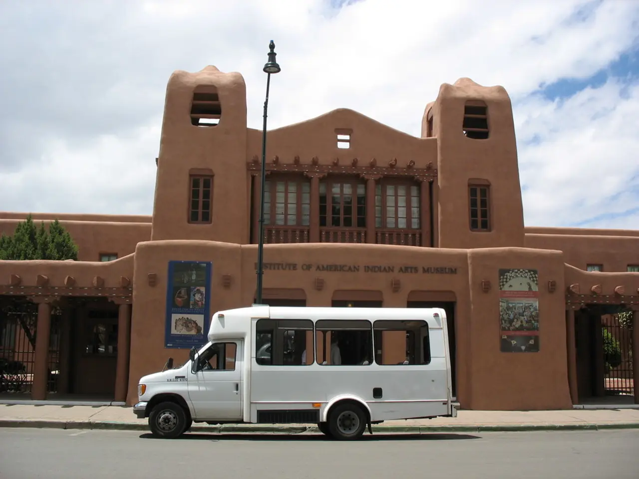 In this picture there is a white truck which is parked near to the street light. In the back there...