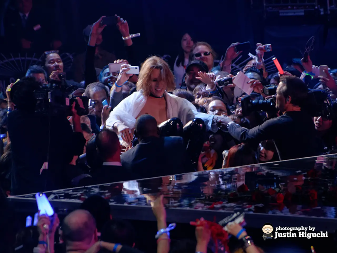 In the center of the image there is a stage. Behind the stage there are people and there is some...