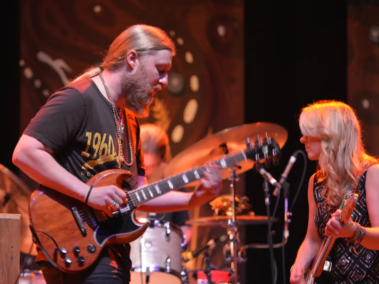 This picture describes about musicians, a man and a woman is playing guitar, in the background we...