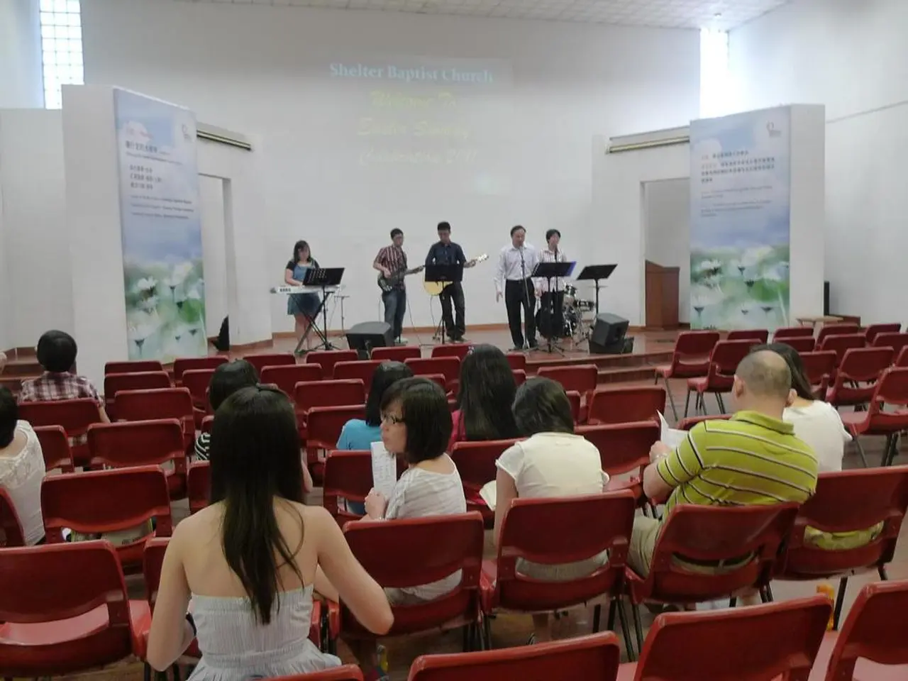 A picture of a auditorium. On this stage middle two persons are playing guitar and the corner...