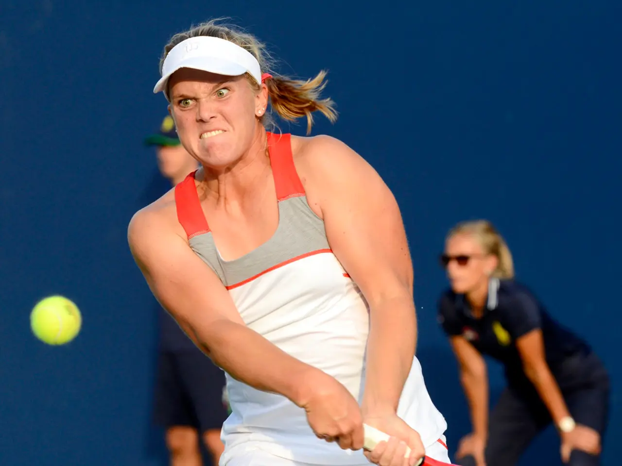 In the center we can see one person holding racket. On the left we can see ball. Back we can see...