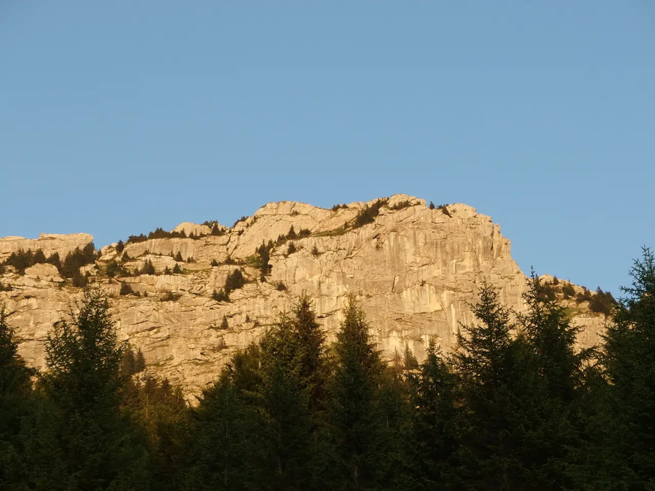 In this image, there are a few hills. We can see some trees and the sky.