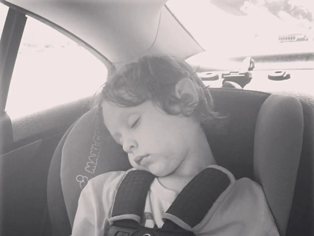 In this image there is a boy sleeping inside the car.