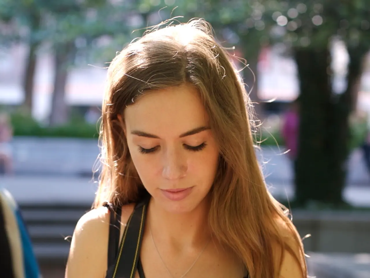 The woman here is catching a camera in her hand and she is wearing a black color top or a dress....