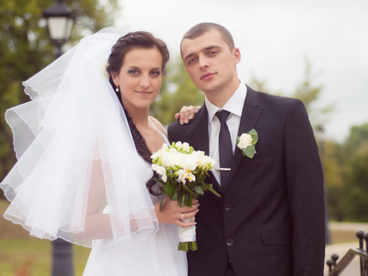 In this image there is a man and woman standing together wearing wedding costumes, where woman is...