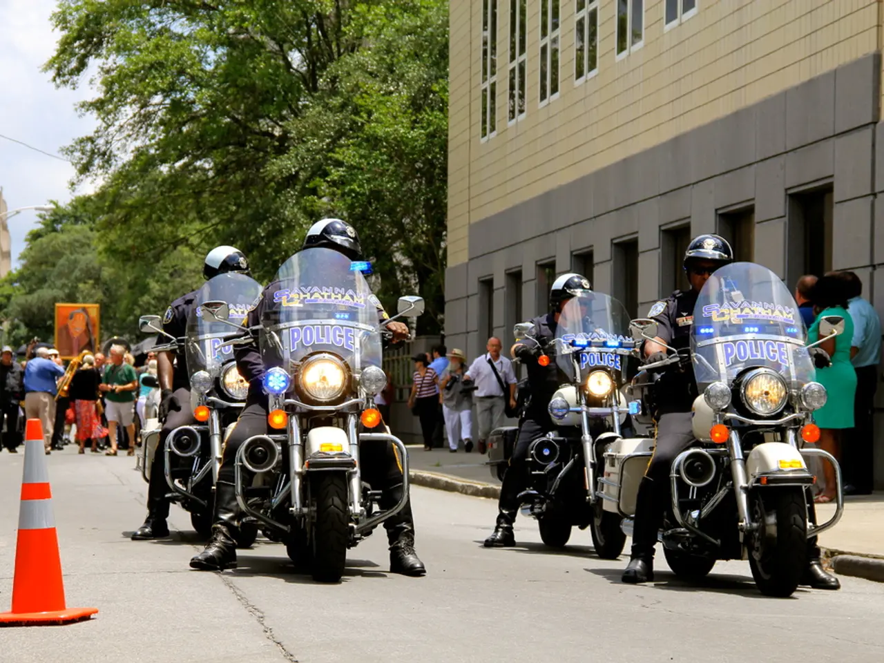 Here 4 police are riding the bikes on the road. In the right side there is a building, in the...