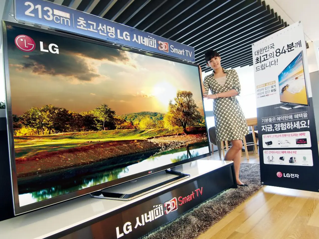 The woman in white and black dress is standing beside the television. Beside her, we see a smart...