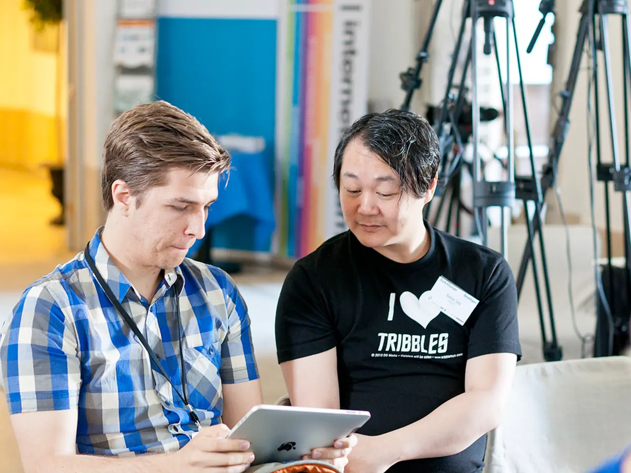 Here we can see two men and he is holding a apple device with his hands. There are stands and a...