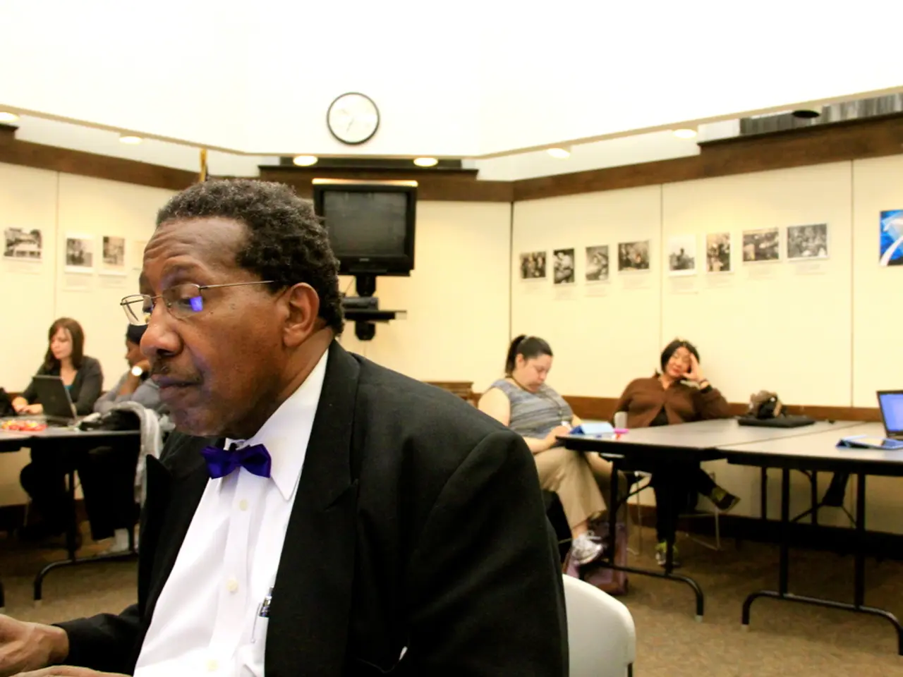 In this image there are five members sitting on the chair. On the table we have laptop. At the...