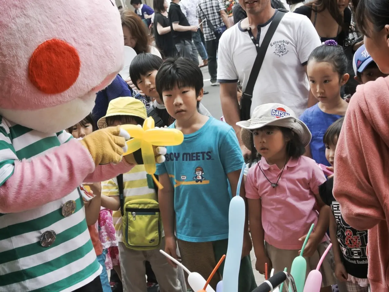 In this picture we can see many kids and people watching a toy in the hand of a person wearing a...