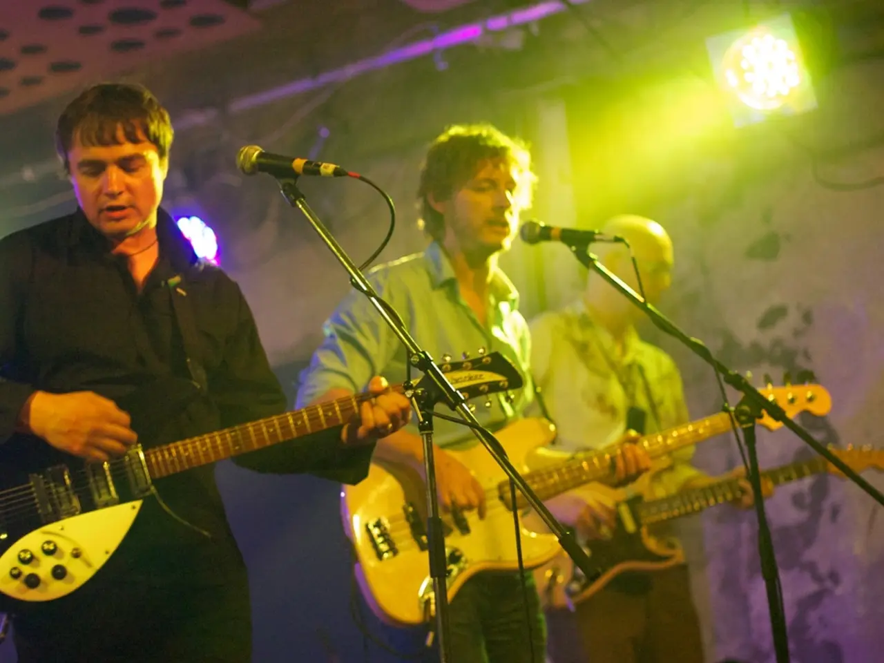 This is a picture taken on a stage, there are three persons holding a music instrument and singing...