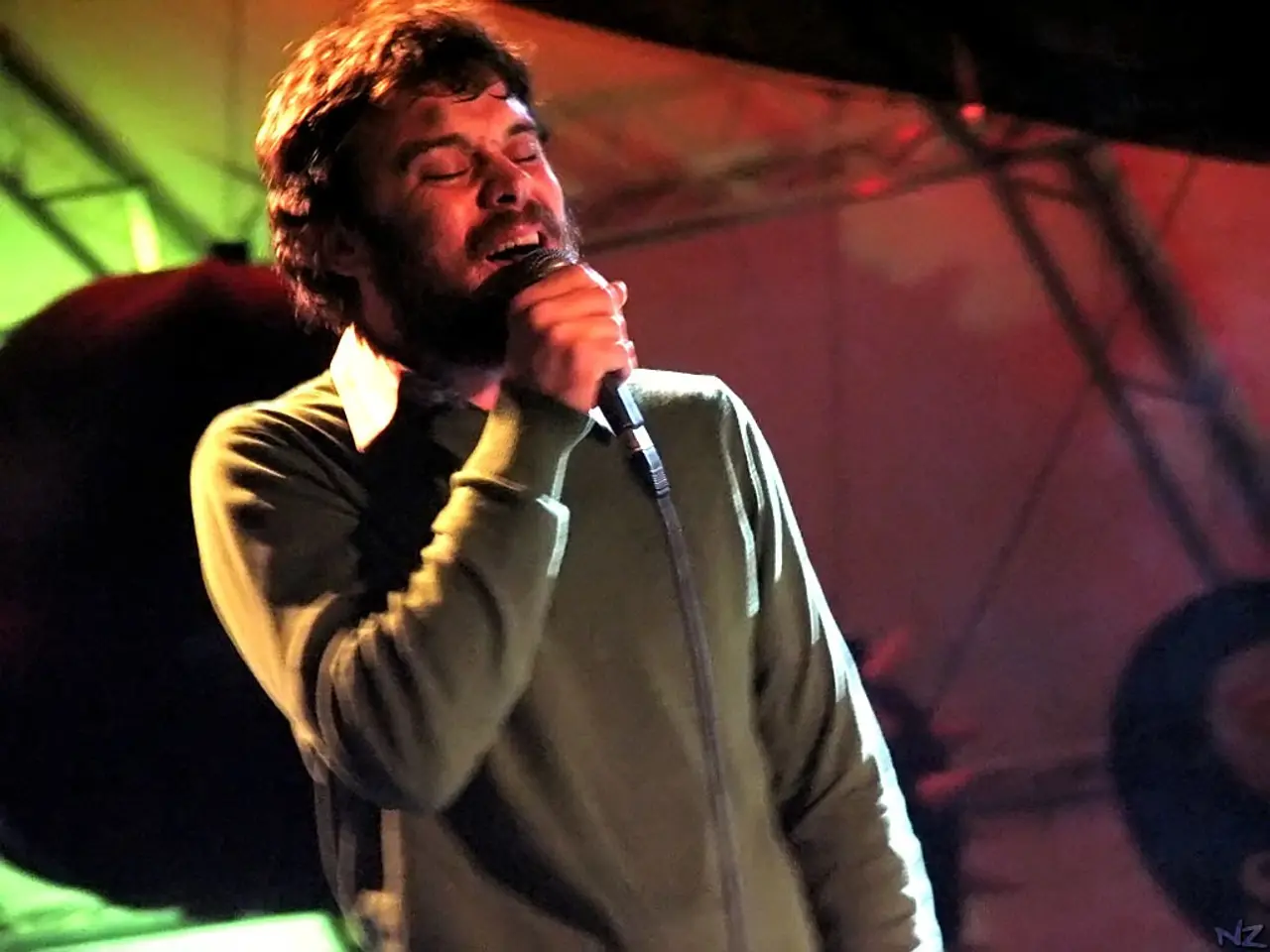 One person is standing and singing a song in the microphone and wearing a grey shirt in the...