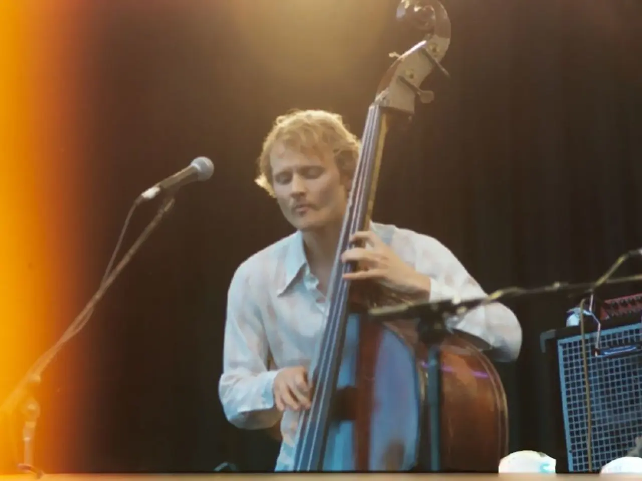 This picture shows a man performing with a violin and a microphone in front of him