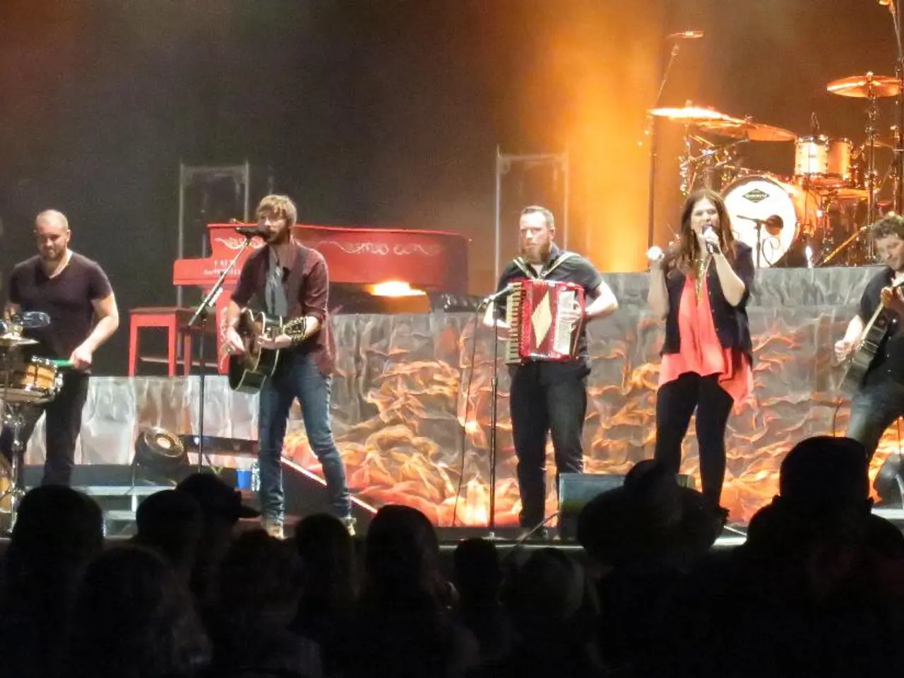 There are group of people playing music and two among them is singing in front of a mic, In...