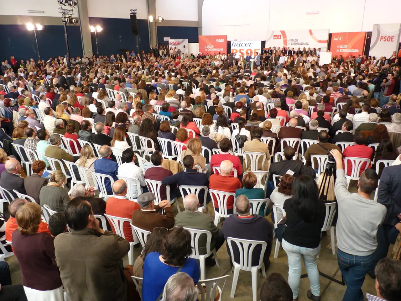 In the picture there is stadium in which many people are sitting on the chair some people are...