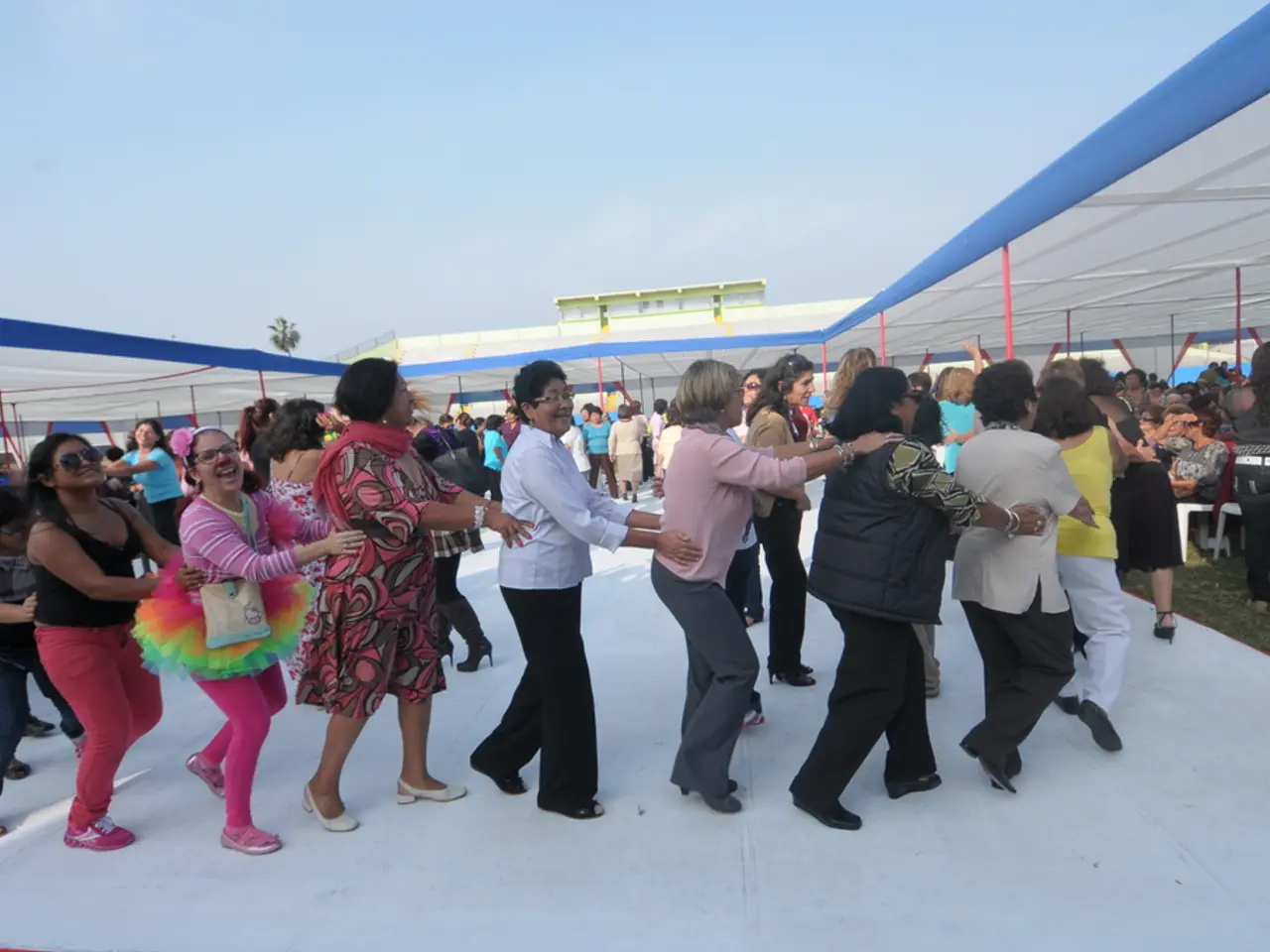 In this picture I can see some people are under the tents and few people are playing on the white...