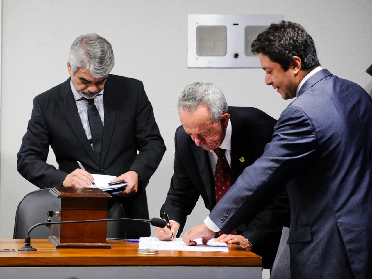 There are three members in this picture. The guy in the middle was writing something on the paper...