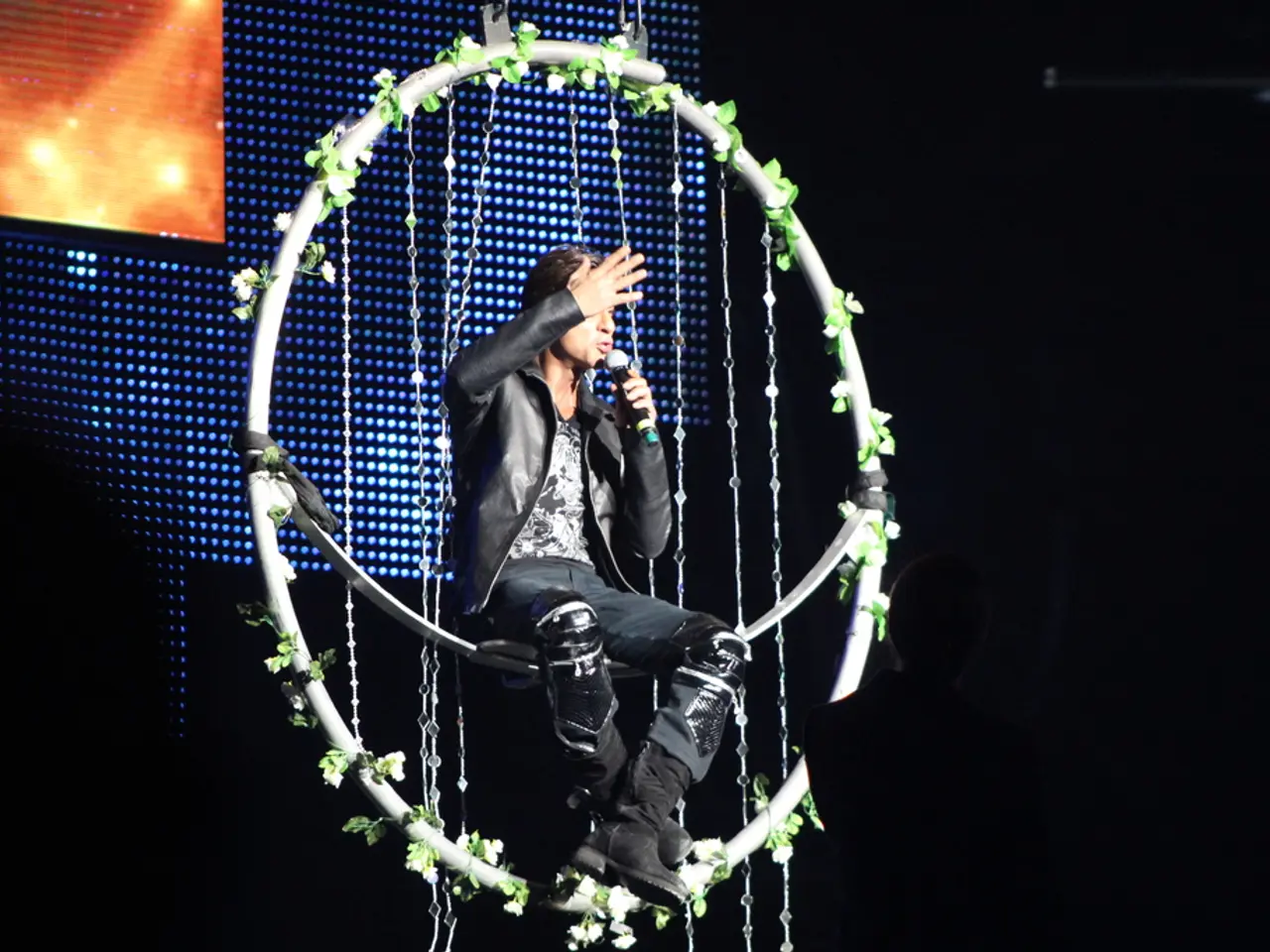 This is the man holding a mike and sitting. This looks like a cyr wheel, which is decorated with...
