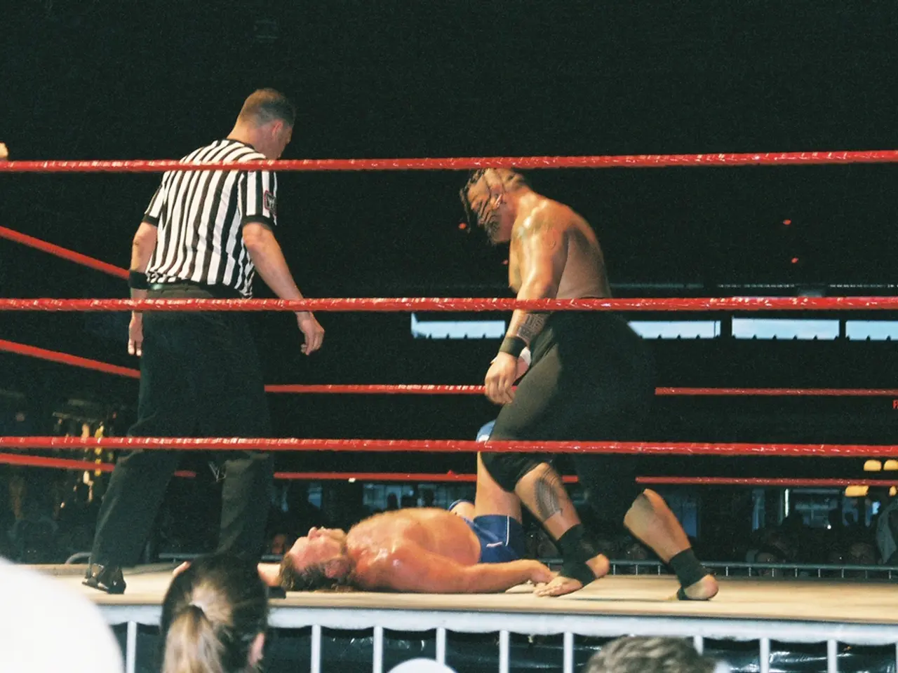 In this there are two fighters in the ring. Beside there is a man wearing white and black strip...