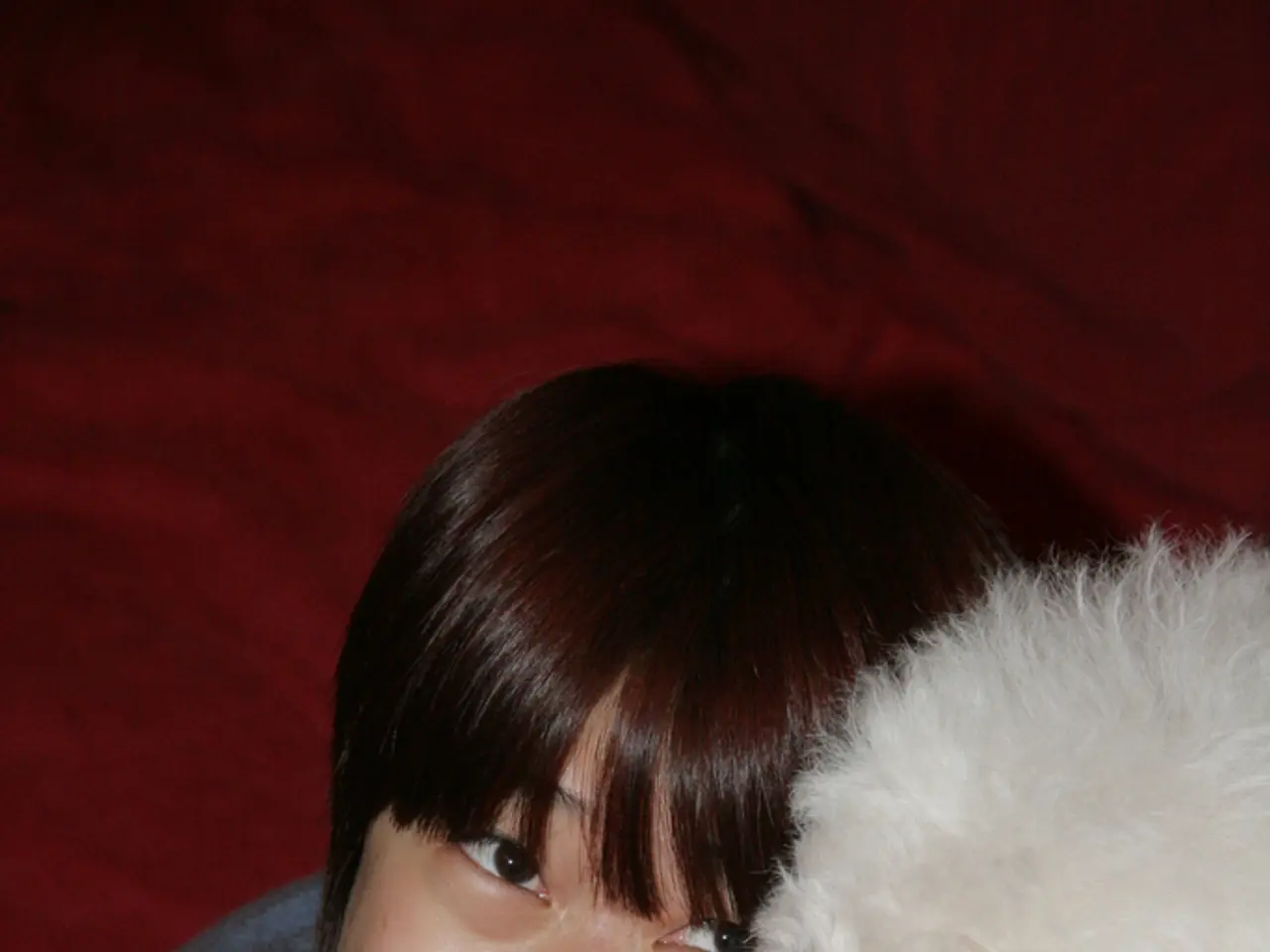 In this image a woman is smiling and holding a pet in her arms.