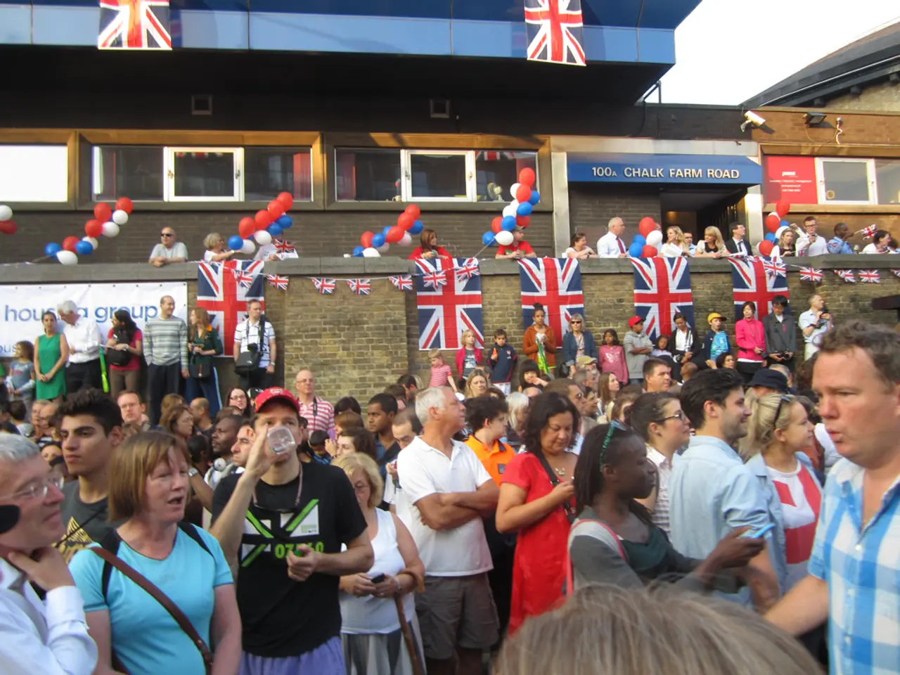 In this image there are group of persons. In the background there are flags hanging on the wall...