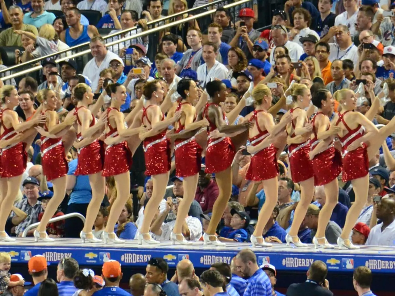 In the center of the image we can see girls dancing. In the background there is crowd sitting.