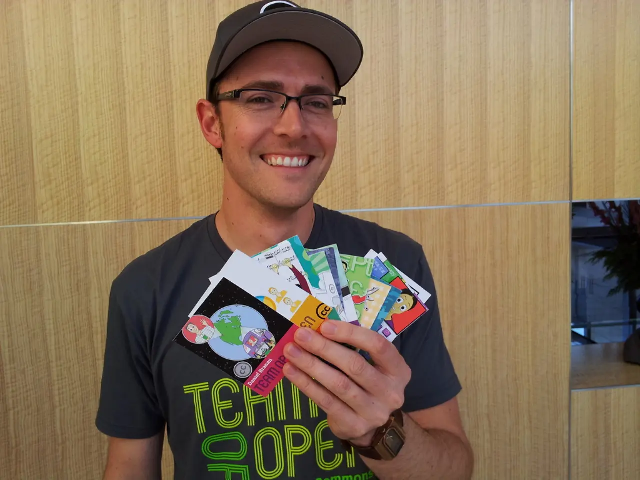 In this image there is a person with a smile on his face, holding some cards in his hand.