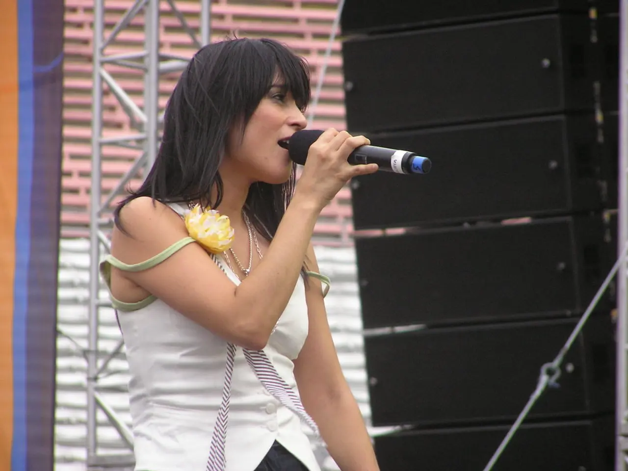 This picture shows a woman standing and singing with the help of a microphone