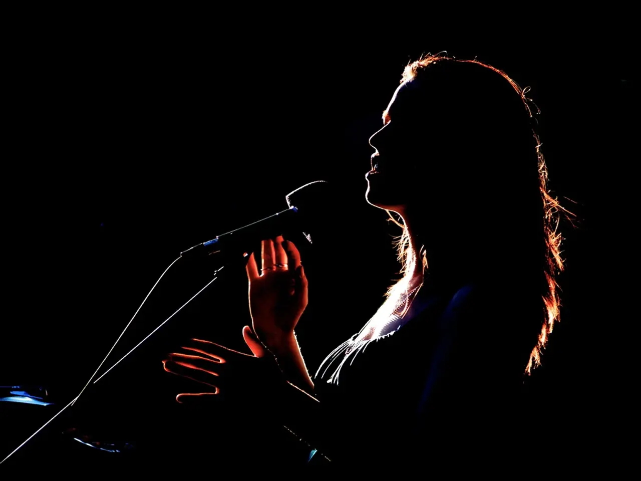 In this image we can see there is a girl singing in microphone.