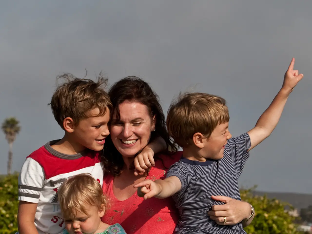 This is an outside view. In this image, I can see a woman and three children are smiling. The woman...