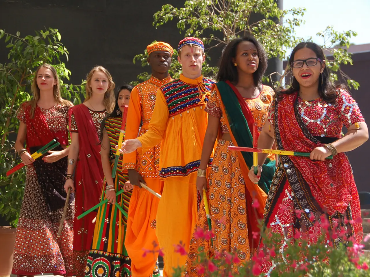 In this image we can see some group of lady persons wearing traditional attire also holding dandiya...