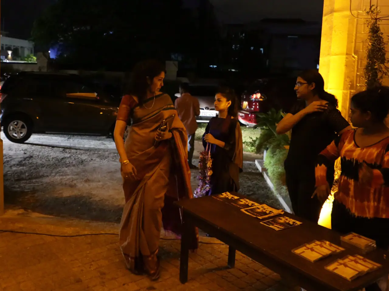 There is woman who is wearing a sari and holding a purse. On the bottom right corner there is a...