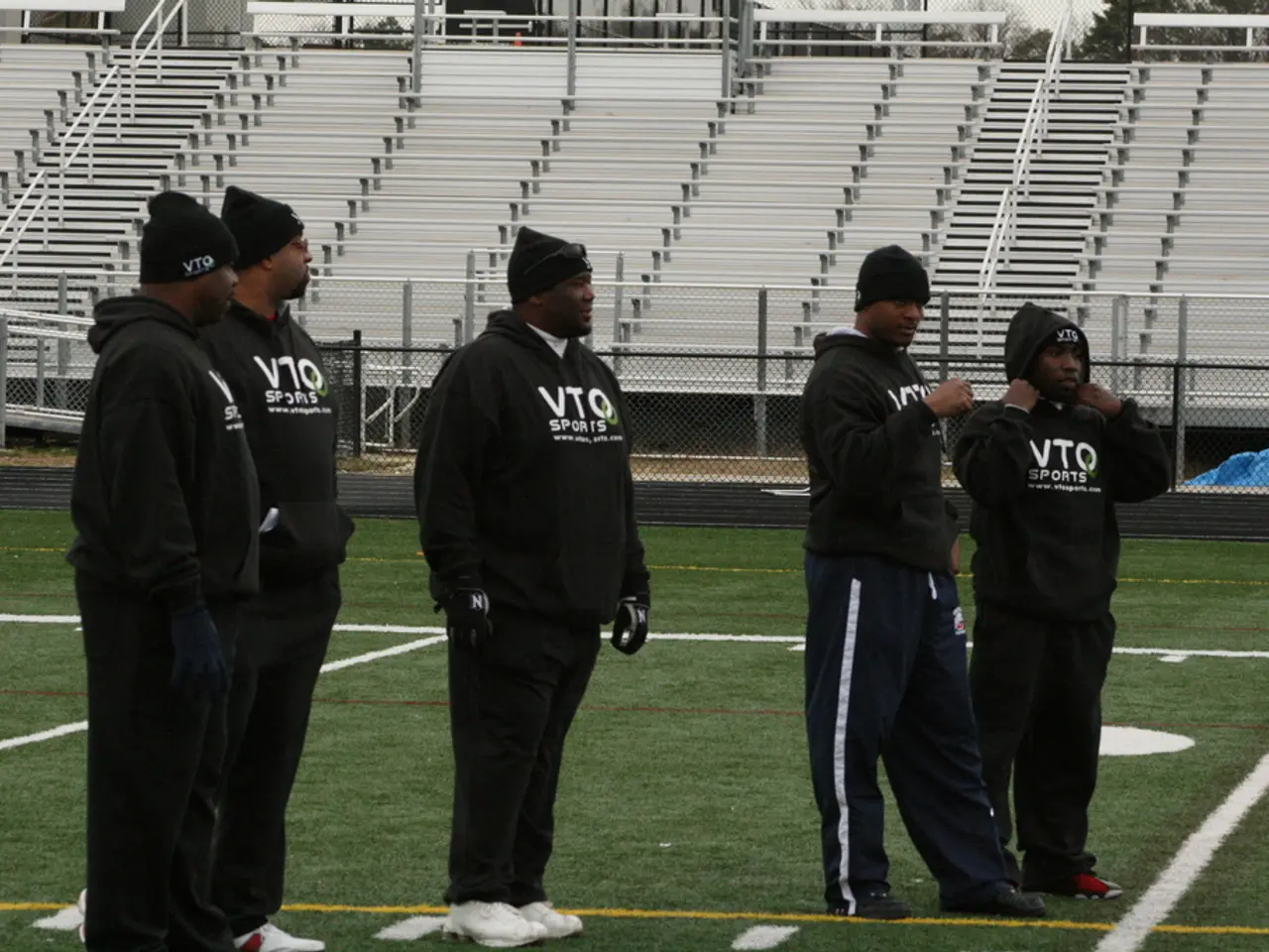 This is a playing ground. Here I can see few men wearing jackets, caps on the heads, standing...