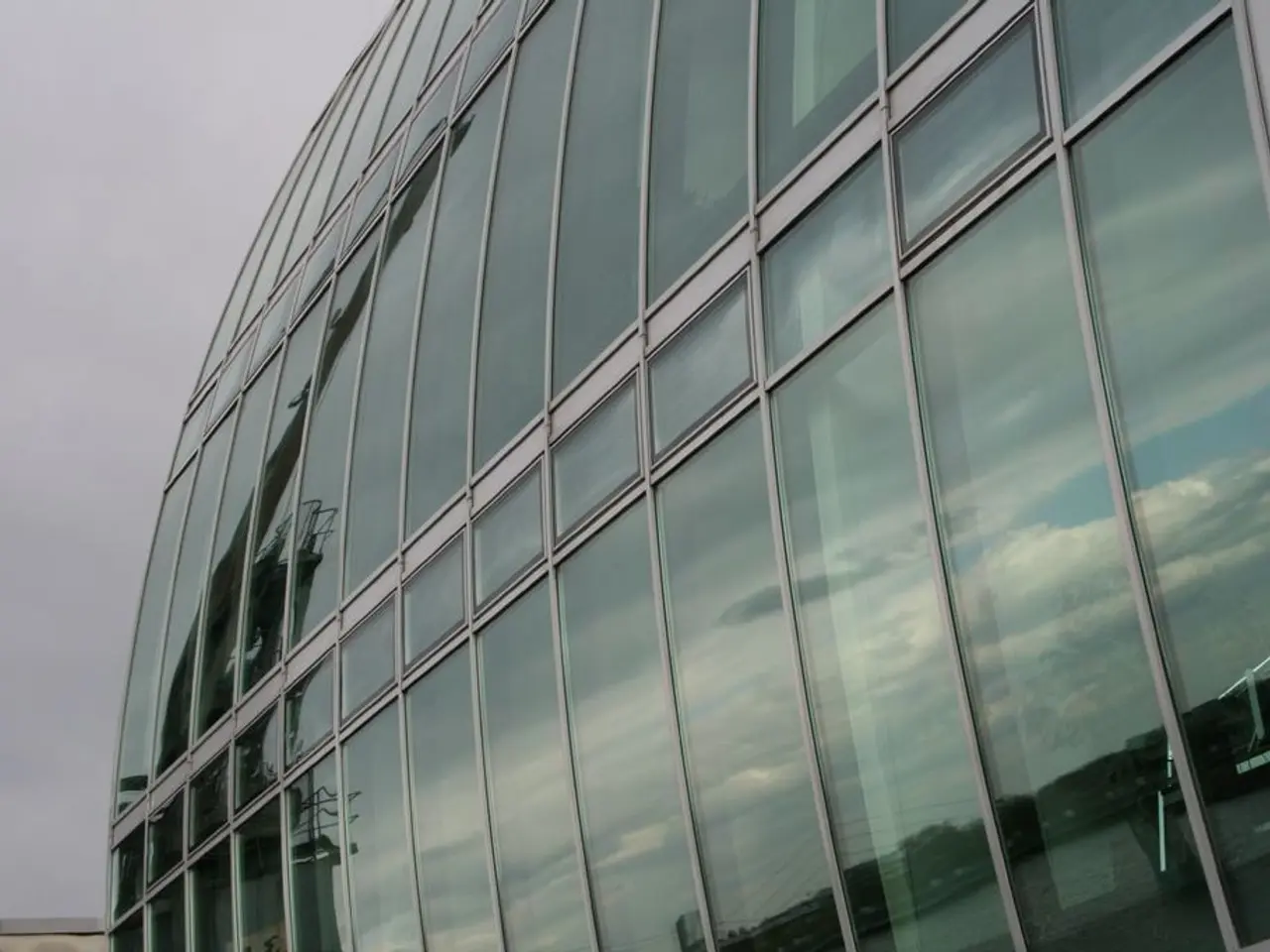 In this picture there is a huge glass corporate building. Behind there is a blue sky.