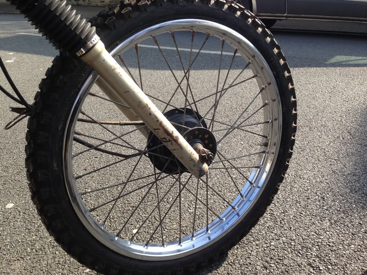 In this image we can see a tire of a vehicle. At the bottom of the image there is road.