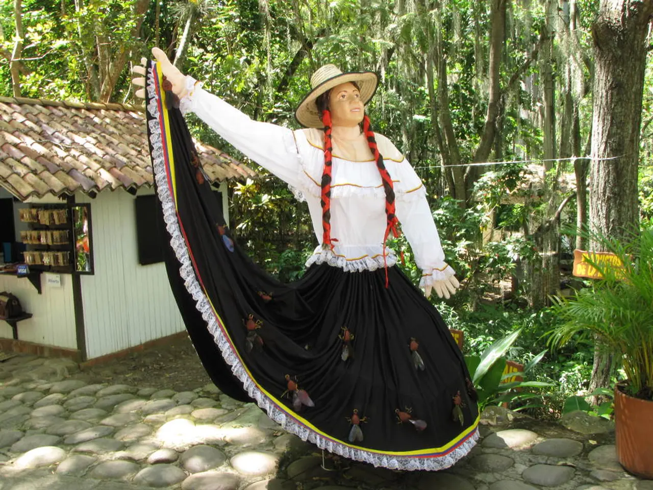 In this image we can see a statue wearing a hat. In the back there is a shed. Also there are trees....