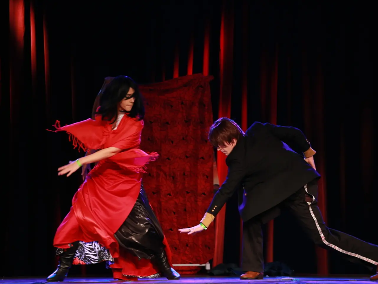 In this image, we can see people wearing costumes and are on the stage. In the background, there is...