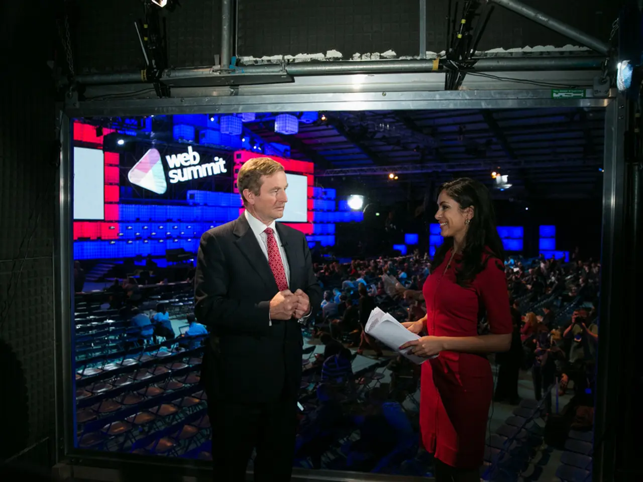 In this image I see a man who is wearing suit and I see a woman who is wearing red color dress and...