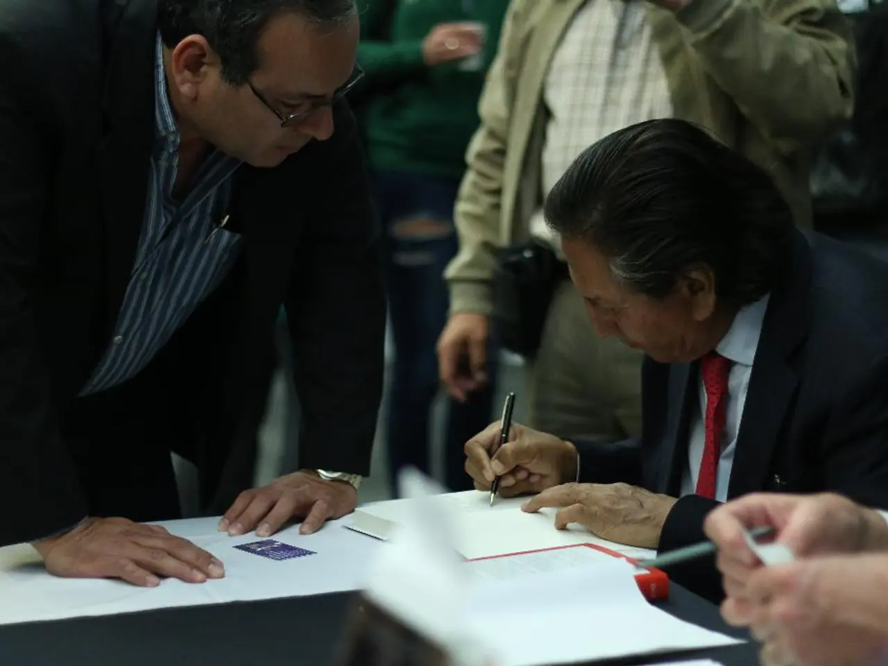 In this image I can see, on the right side there is an old man writing something on the book, and...