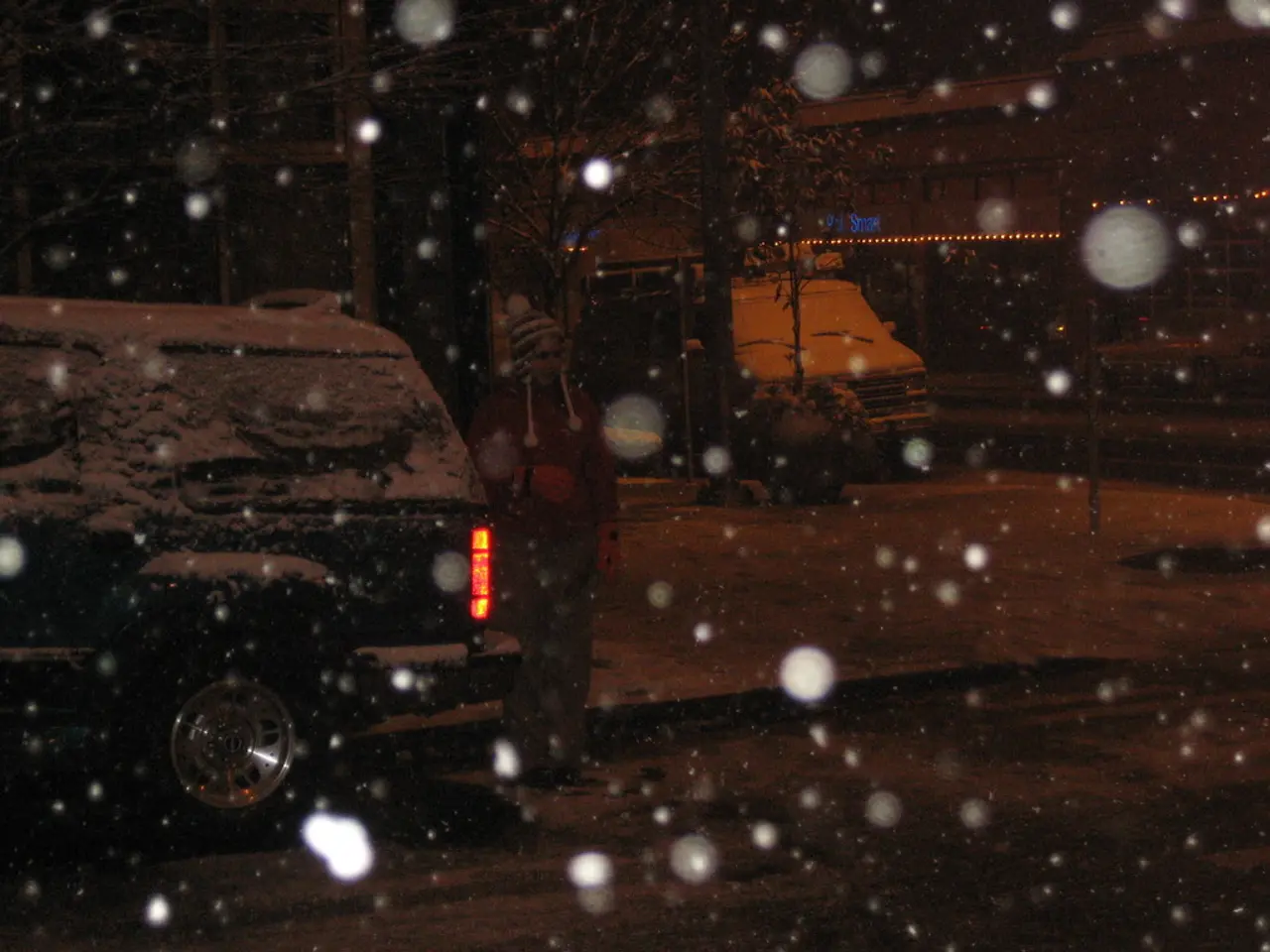 This is an image clicked in the dark. Here I can see the snowfall and there are two vehicles on the...