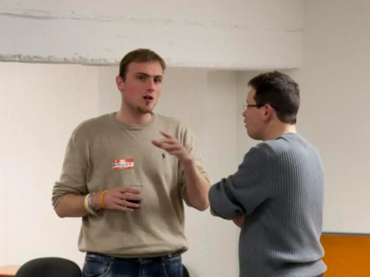 There are two people standing on the floor and one of them is talking to the other and holding a...