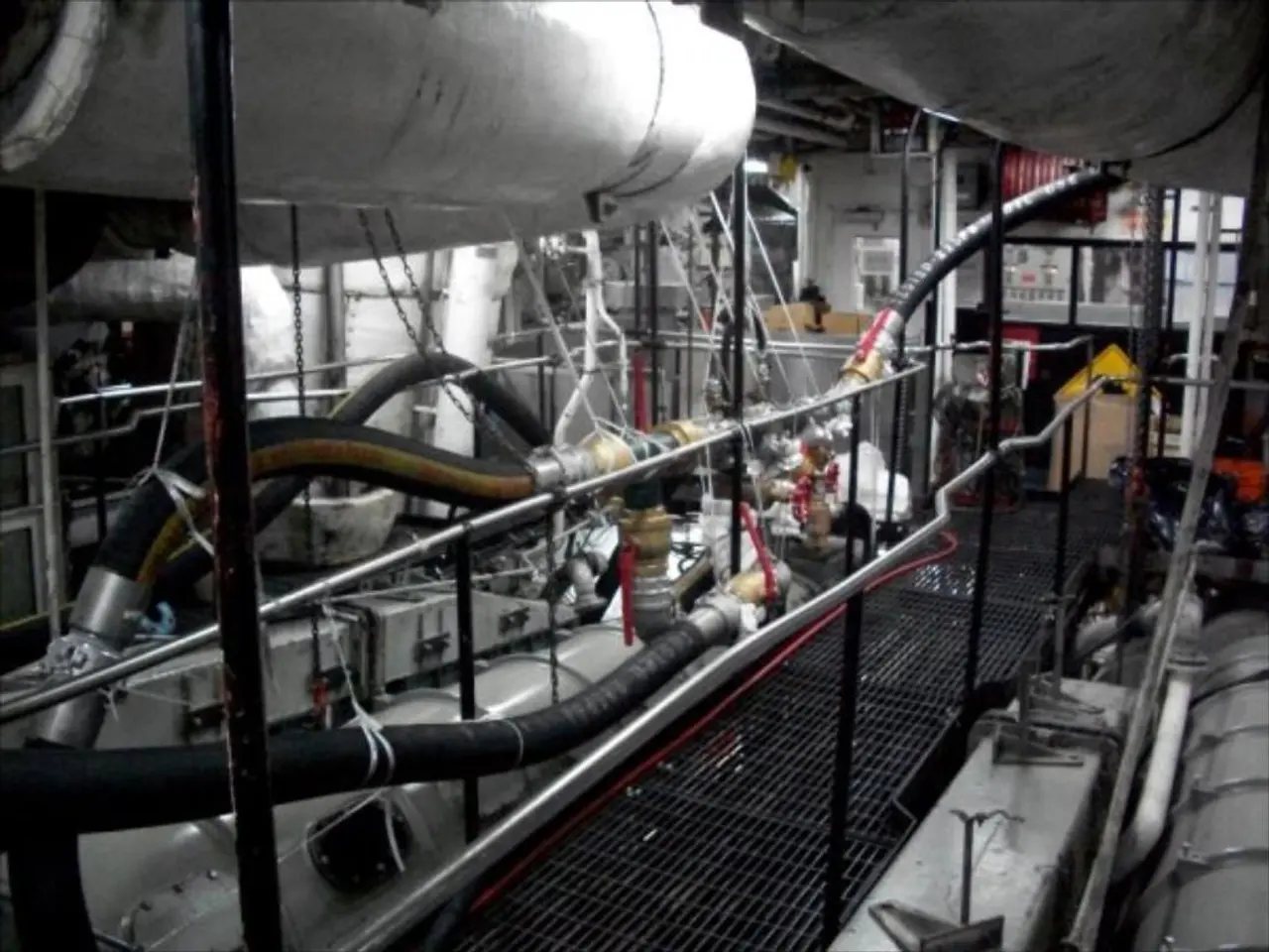 In this image I can see black color pipes, a fence and some other machines.