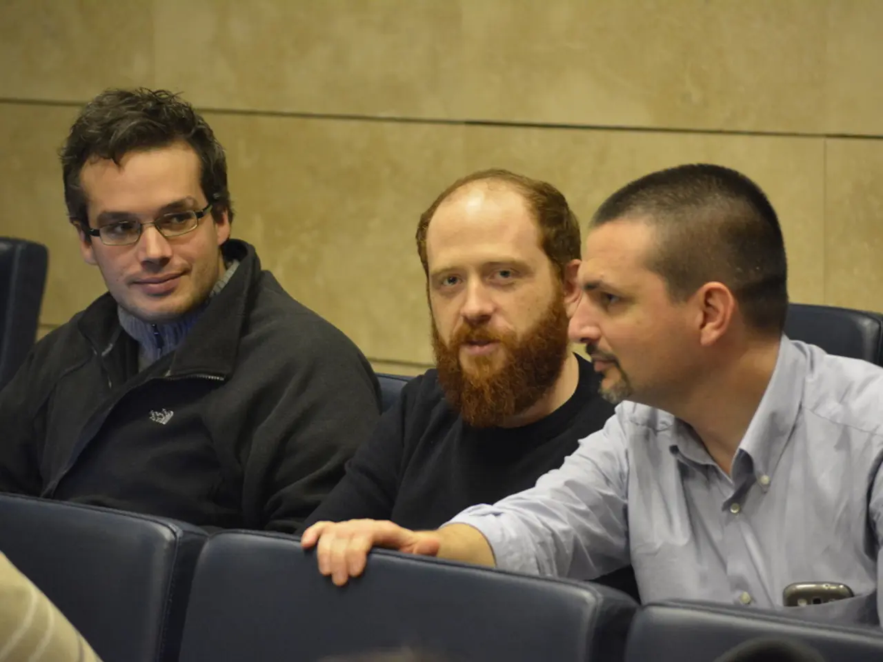 In this image we can see men sitting on the chairs.