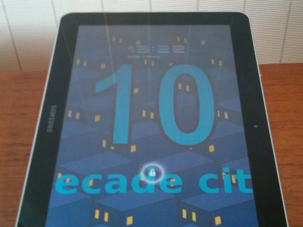 In this picture we can see a tab placed on a wooden table and in the screen of a tab we can see...