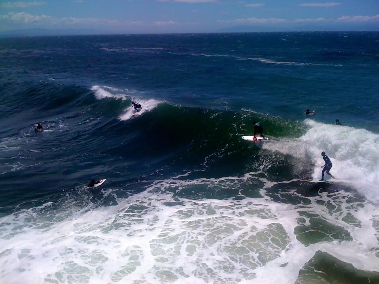 In this picture we can see people surfing with the surfboards on the water. At the top of the...