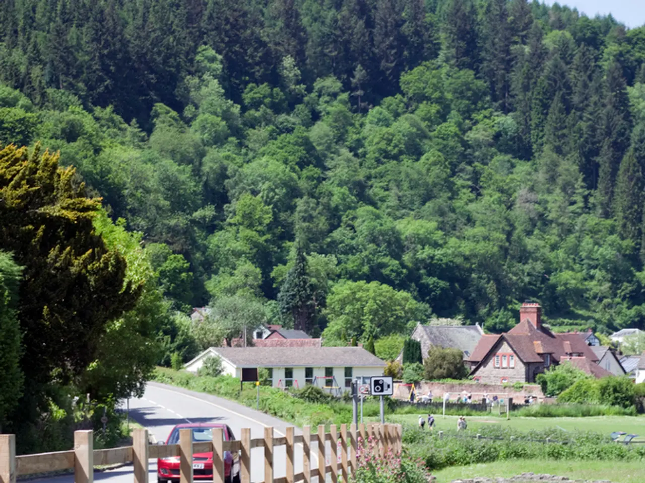 In this image we can see a car travelling on the bridge, at the back there are trees, here is the...